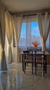 a dining room with a table and chairs and a large window at Furahi Apartment in Mombasa