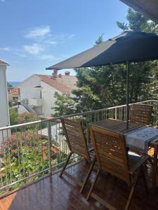 a table and chairs on a balcony with an umbrella at Apartmani Krk in Krk