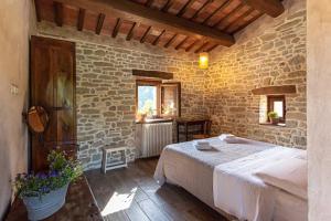 ein Schlafzimmer mit einem Bett und einer Steinwand in der Unterkunft Borgofortino in Montefortino