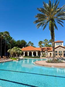 a swimming pool with a palm tree in front of a house at Florida Vacation Condo - No Resort Fees in Kissimmee