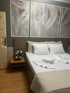 a bedroom with a bed with white pillows and a picture at Bed & Coffee LUKAS Krusevac in Kruševac