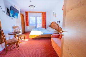 a bedroom with a bed and a couch and a tv at Minzlhof in Ramsau am Dachstein