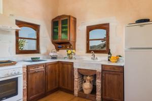 a kitchen with wooden cabinets and a white refrigerator at Kamares Private Pool stone Villa in Makhairoí