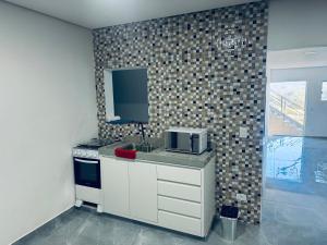 a kitchen with a sink and a microwave on a counter at Refúgio dos ventos in Campos do Jordão