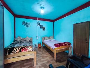 two beds in a room with blue walls at Betzer homestay in Cherrapunji