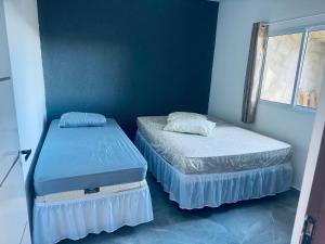 two beds in a room with blue walls at Refúgio dos ventos in Campos do Jordão