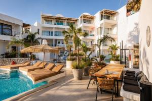 an outdoor patio with tables and chairs and a swimming pool at Kouros Home & Suites--Faliraki--Adults Only in Faliraki