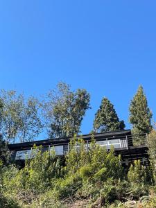 a house on a hill with trees in the background at Cabaña Puelo-Cochamó Tiny house in Sotomó