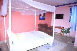 a bedroom with a white canopy bed and a table at La Bella resort in Mombasa