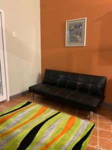 Eine schwarze Couch steht in einem Zimmer mit Teppich. in der Unterkunft Bamboo View in Loango