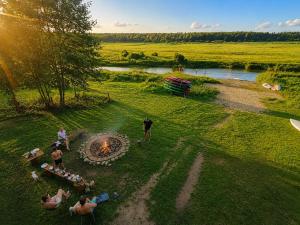 a group of people sitting around a fire in a field at Domki nad rzeką Narew in Ploski