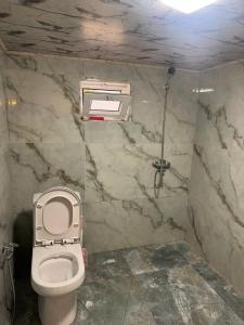 a bathroom with a white toilet and a marble wall at xanagah aframe in Qala