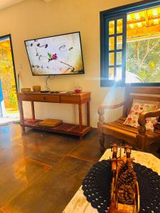 a living room with a table and a painting on the wall at Cheiro de Flor - Gamarra in Baependi