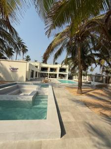 a building with a swimming pool and palm trees at Atlantic Shores Resort in Igbolobi