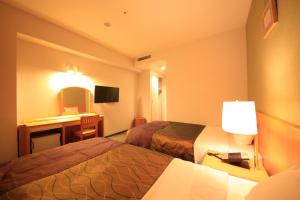 a hotel room with two beds and a desk at Hotel Grand City in Tokyo