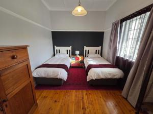 a bedroom with two beds and a red rug at Beach Street Self-Catering in Mossel Bay +14 photos