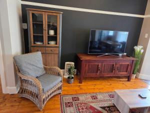 a living room with a television and a wicker chair at Beach Street Self-Catering in Mossel Bay