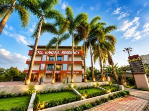 a hotel with palm trees in front of it at Hotel Kanaka Residency in Mangrul
