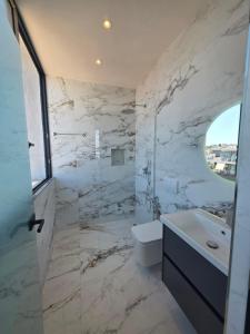 a white bathroom with a sink and a toilet at Rooftop panoramic jacuzzi room in Ksamil +11 photos