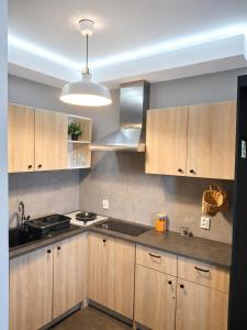 a kitchen with wooden cabinets and a sink and a stove at Apartament na Wzgórzu in Wieliczka +3 photos