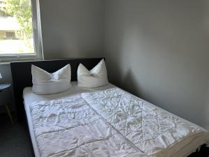 a bed with white sheets and pillows next to a window at Ferienhaus Katja in Göhren
