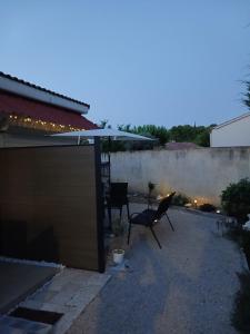 a patio with an umbrella and two chairs and a table at Mayka in L'Isle-sur-la-Sorgue