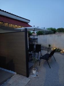 a patio with two chairs and an umbrella at Mayka in L'Isle-sur-la-Sorgue