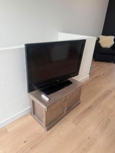 a flat screen tv on a wooden stand in a living room at Modern Design Apartment with Balcon in Nijmegen