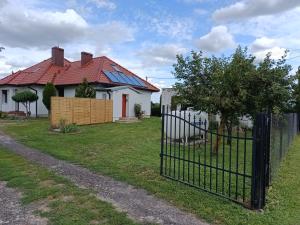 a fence in front of a white house with a red roof at Wzgórze za miedzą - Niezależne Studio z osobnym wejściem in Sicienko