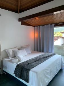 a bedroom with a white bed with a window at Mansão Mascarenhas in Lençóis