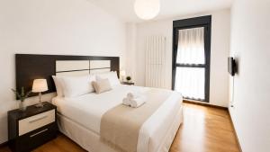 a bedroom with a large white bed with a teddy bear on it at Apartamento Golf Rioja Alta in Cirueña +26 photos