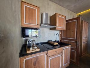 a kitchen with wooden cabinets and a black counter top at Les Terrasses Suites in Calheta