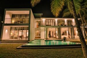 a large house with a swimming pool in front of it at Infinity Whisper in Kosgoda