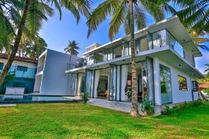 an exterior view of a house with palm trees at Infinity Whisper in Kosgoda