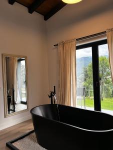 a black bath tub in a room with a window at Aer & Rowa Chalets by Ekow in Statjunea Borsa