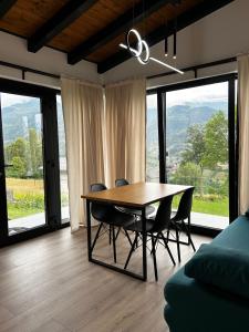 a dining room with a table and chairs and windows at Aer & Rowa Chalets by Ekow in Statjunea Borsa