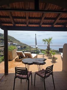 a table and chairs on a patio with a view of the ocean at Les Terrasses Suites in Calheta