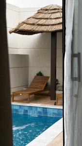 a pool with a straw umbrella and a bench next to it at شاليهات رفا in Taif +6 photos