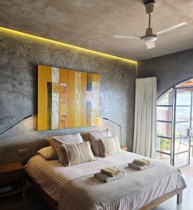 a bedroom with a bed with a painting on the wall at Les Terrasses Suites in Calheta