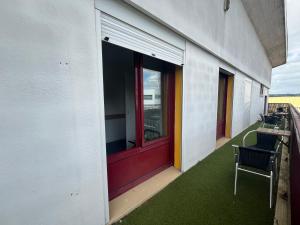 a balcony of a building with a red door and chairs at HOSTEL Les Bois Verts - Les Herbiers in Les Herbiers