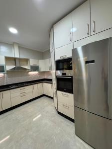 a kitchen with white cabinets and a stainless steel refrigerator at Marina Puerto in Marina Smir +15 photos