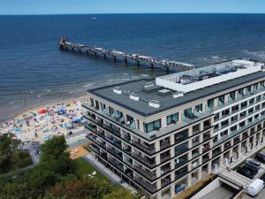 a building next to a beach with a pier at Baltic Infinity Garden Suite 316 - SPA & Pool Access in Międzyzdroje