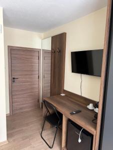 a room with a desk with a television on the wall at Руми in Velingrad