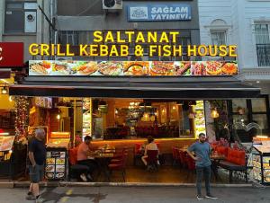 a group of people standing outside of a grill kebab and fish house at Saltanat Apartment in Istanbul