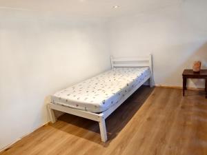 a white bed in a room with a wooden floor at Shriji Homes in Watford West Station +4 photos