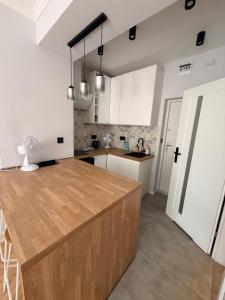 a kitchen with white cabinets and a wooden counter top at Apartament centrum in Białystok +3 photos