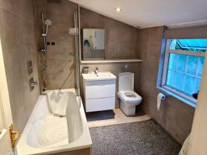 a bathroom with a tub and a sink and a toilet at Shriji Homes in Watford West Station