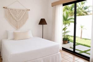 a bedroom with a white bed and a large window at The White Villa in Cancún