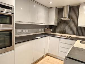 a kitchen with white cabinets and stainless steel appliances at Shriji Homes in Watford West Station