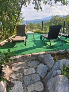 two chairs and a table on a green lawn at Apartments Bosket in Kastav